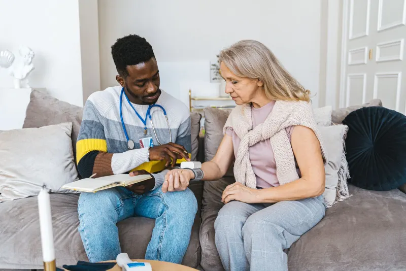 Healthcare professional checking an elderly woman’s blood pressure at home